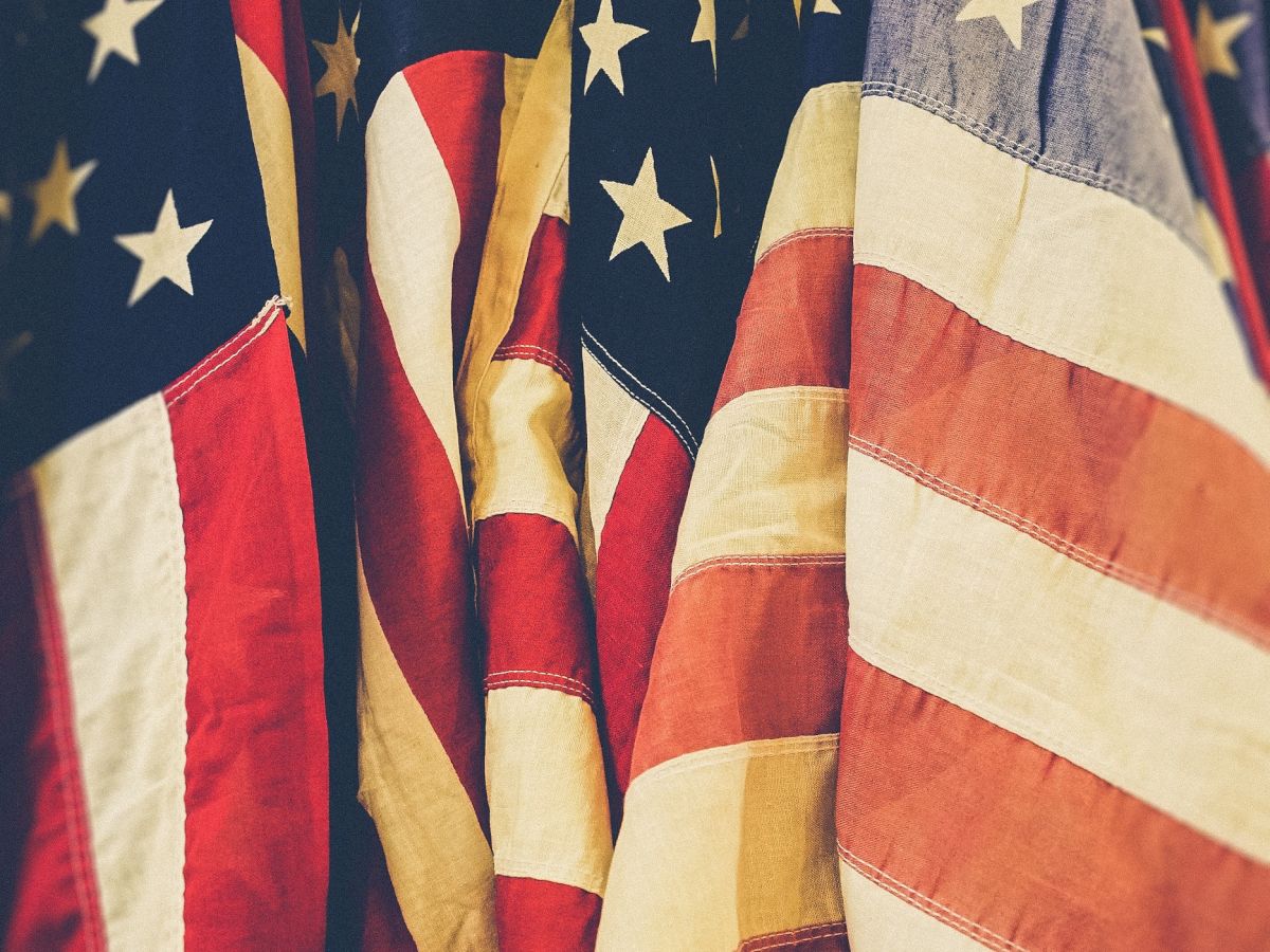 The image shows multiple American flags tightly packed together, displaying the stars and stripes pattern prominently.