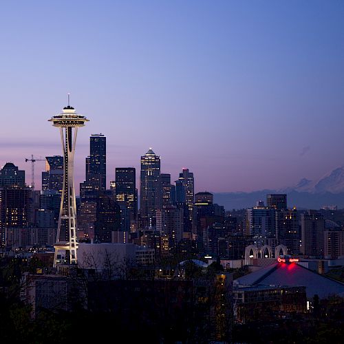 A twilight view of Seattle’s skyline, featuring the Space Needle prominently with Mount Rainier visible in the background.